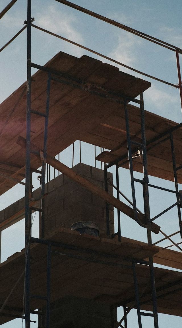 Scaffolding against the sky with a worker in a hi-vis vest