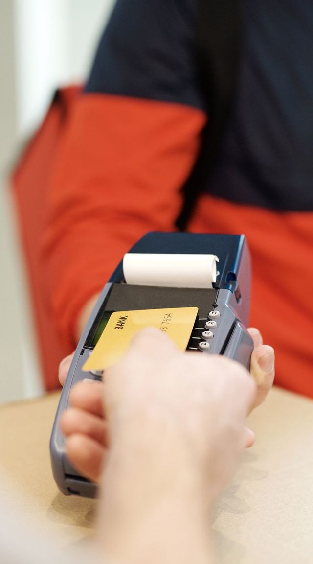 A customer tapping a bank card on a handheld card reader
