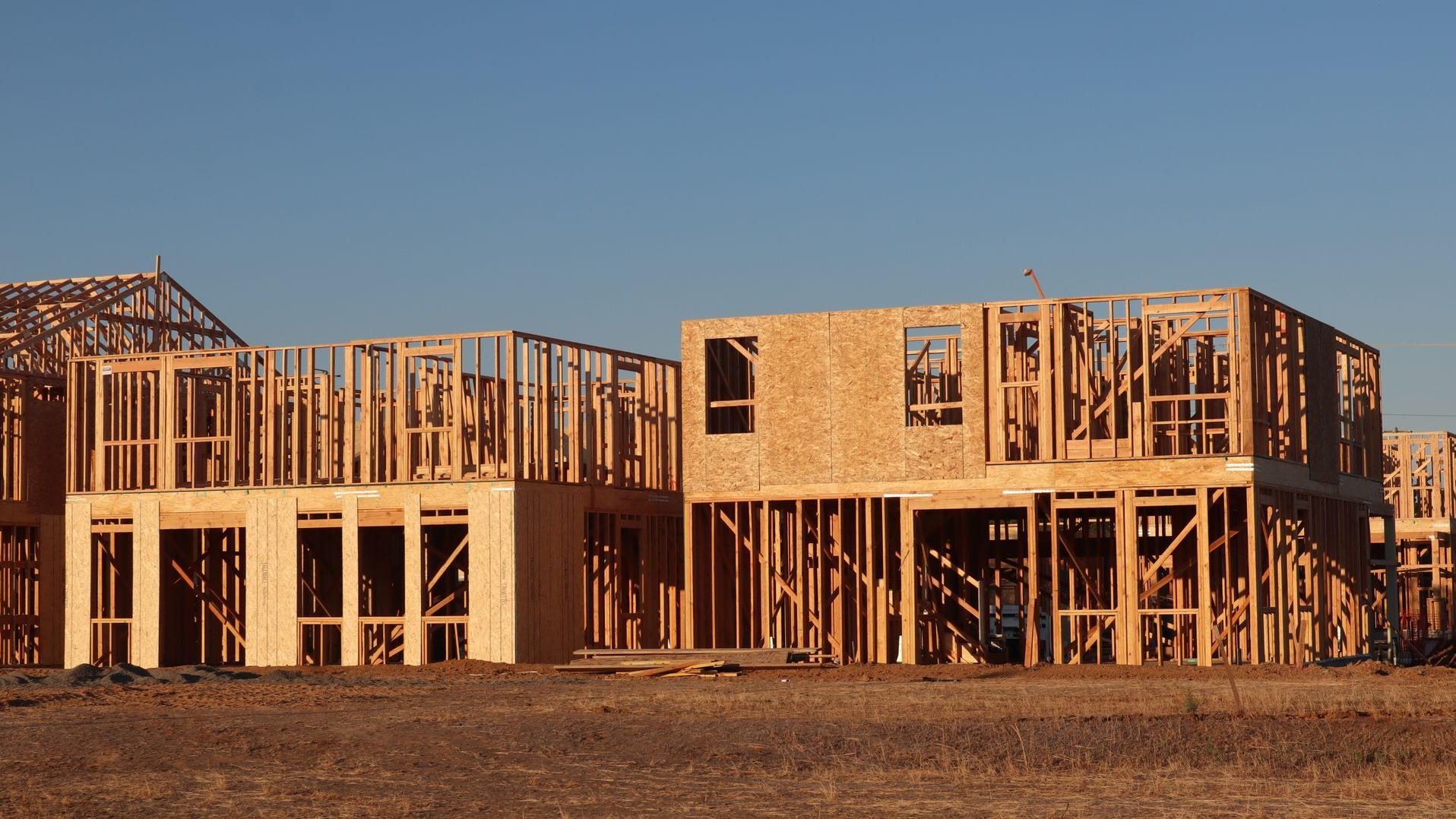 Timber-framed houses under construction in low evening sun