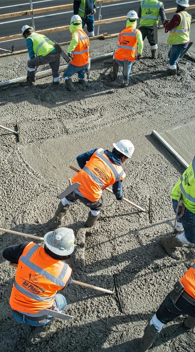 Crew in hi-vis vests and hard hats levelling freshly poured concrete, seen from above