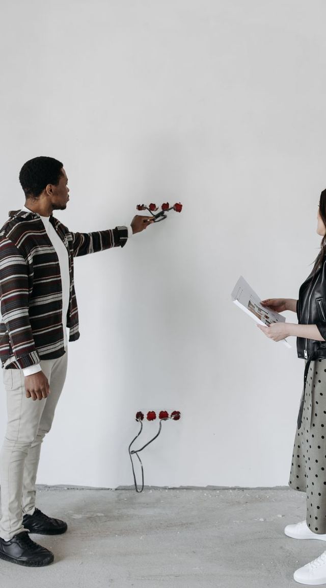 A designer and a homeowner discussing an unfinished room, the homeowner holding a tablet