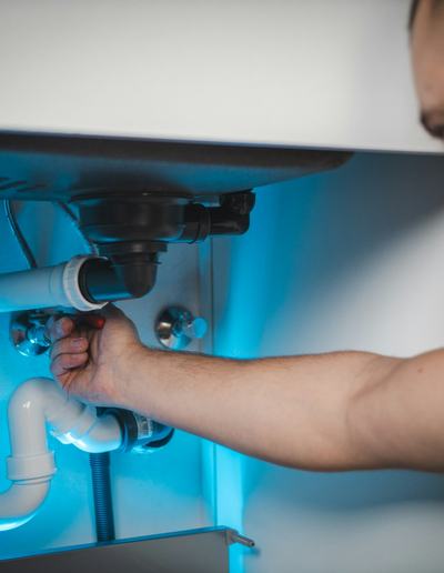 Plumber fitting a waste pipe under a sink