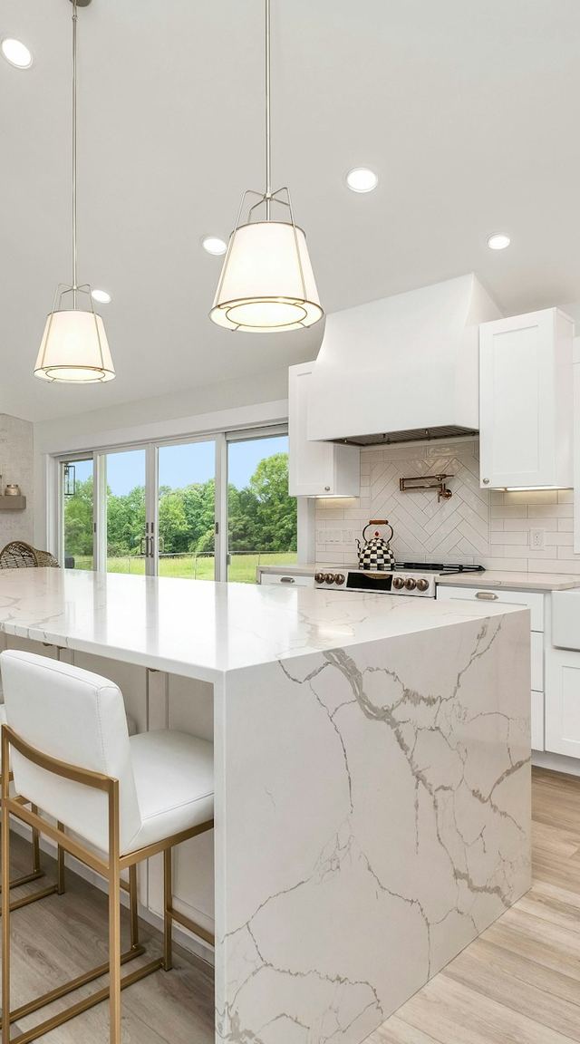 Finished white kitchen with a marble island and pendant lights